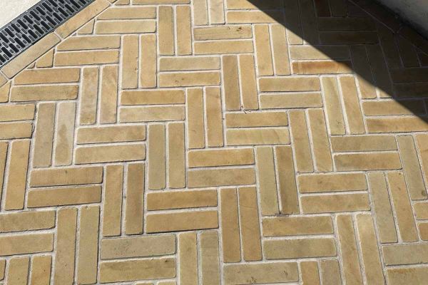 9 Harvest sandstone tumbled patio bricks placed in 3 rows, zigzag pattern, against grey background. Free UK delivery available.***