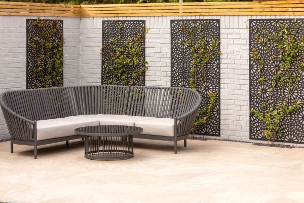Outdoor seating area with Gaja Beige 900x600 Porcelain Paving, framed by gabion wall panels and timber fencing.***