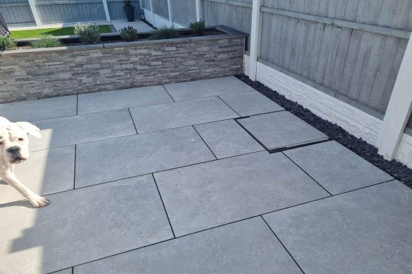 Neat patio layout using Heritage Grey 900x600 Porcelain Paving, set against a raised grey sleeper bed.***
