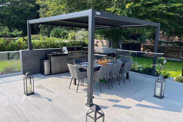 Outdoor dining area with Overland Silver 1200x600 Porcelain Paving, shaded by a sleek pergola.***
