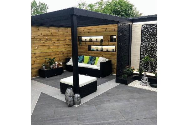 Garden seating area with Overland Dark Porcelain Paving, framed by timber fencing and black pergola.***