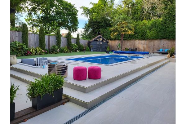 Contemporary garden with Overland Sand 1200x600 Porcelain Paving, surrounding a raised pool and vibrant seating.***
