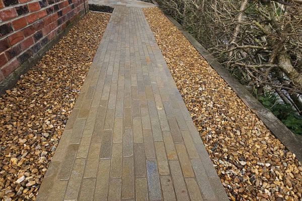 Hand places 11th stone paver at end of 5 courses of 2 Antique Yellow limestone patio bricks in herringbone pattern.***